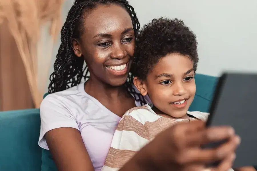 Una madre y su hijo en el sofá mirando juntos la pantalla de una tableta.