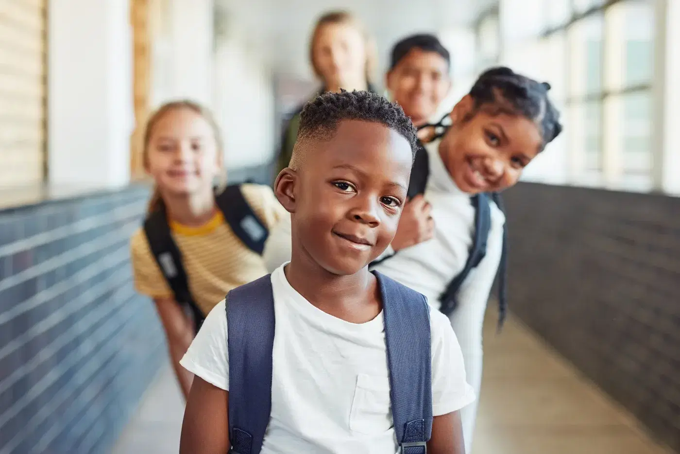 Estudiantes en fila en el pasillo de la escuela, el primero mirando a la cámara