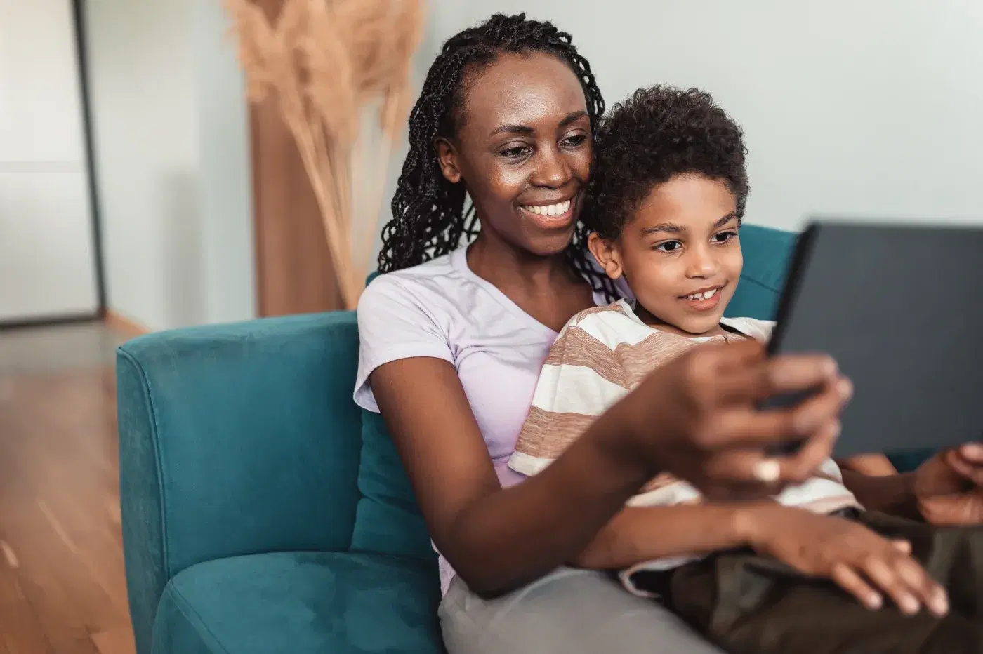 Madre e hijo en el sofá de casa, mirando juntos la pantalla de una tableta